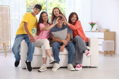 Photo of Happy teenage friends sitting on sofa indoors
