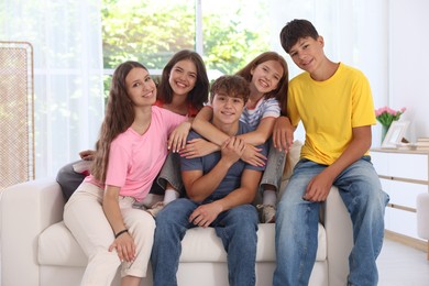Photo of Happy teenage friends sitting on sofa indoors