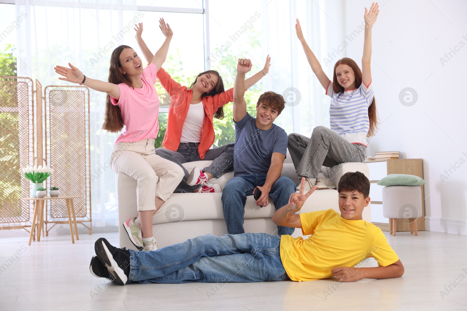 Photo of Happy teenage friends sitting on sofa indoors