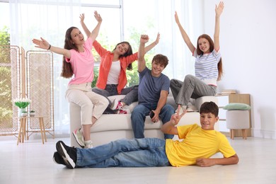 Photo of Happy teenage friends sitting on sofa indoors