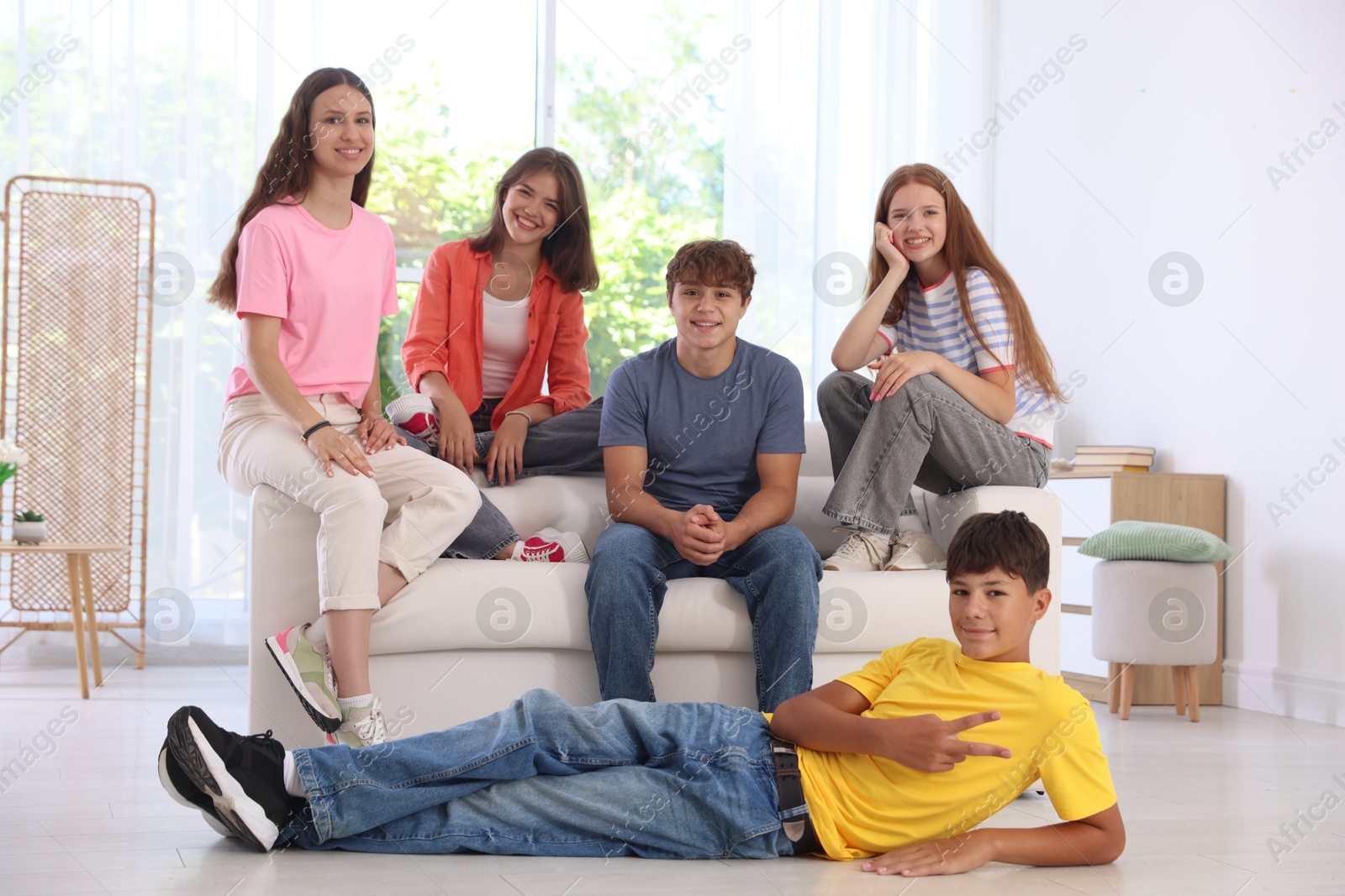Photo of Happy teenage friends sitting on sofa indoors