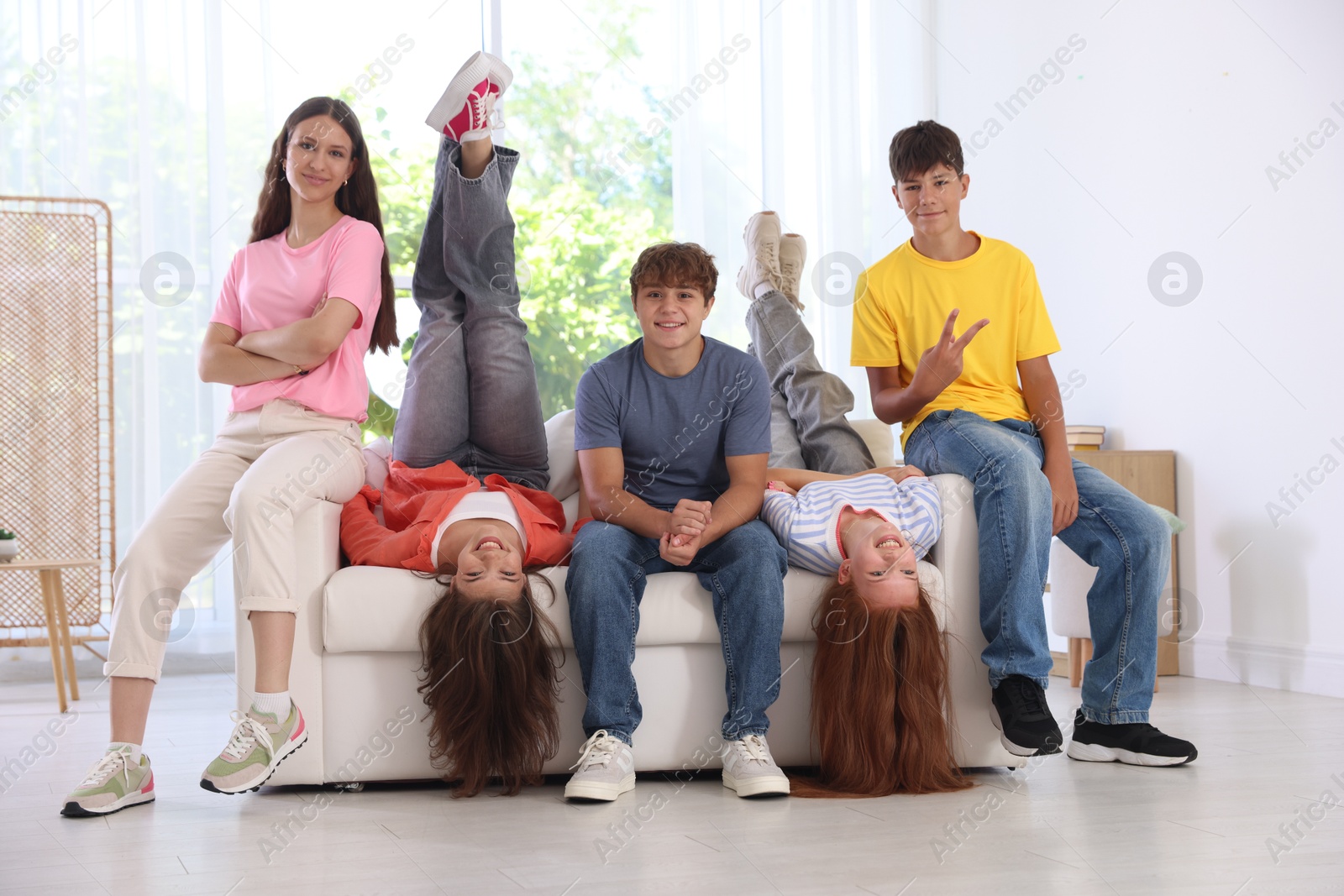 Photo of Happy teenage friends sitting on sofa indoors