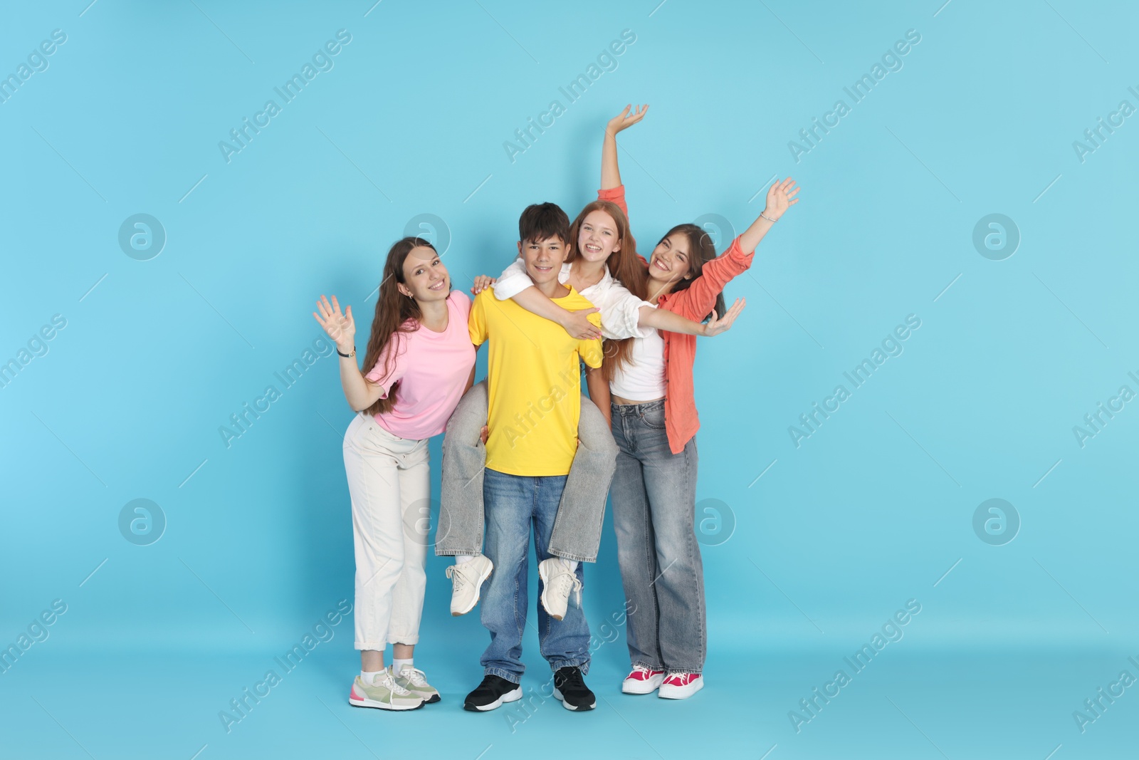 Photo of Full-length portrait of happy teenage friends on light blue background