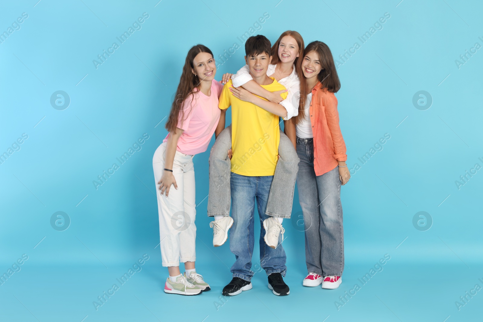 Photo of Full-length portrait of happy teenage friends on light blue background
