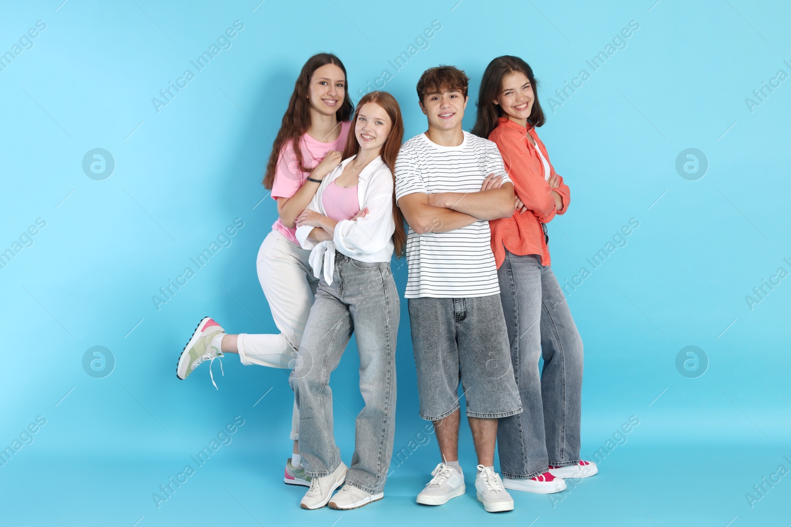 Photo of Full-length portrait of happy teenage friends on light blue background