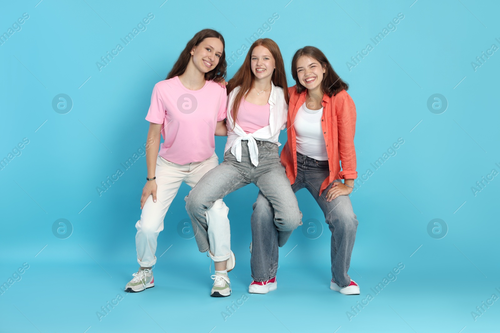 Photo of Full-length portrait of happy teenage friends on light blue background