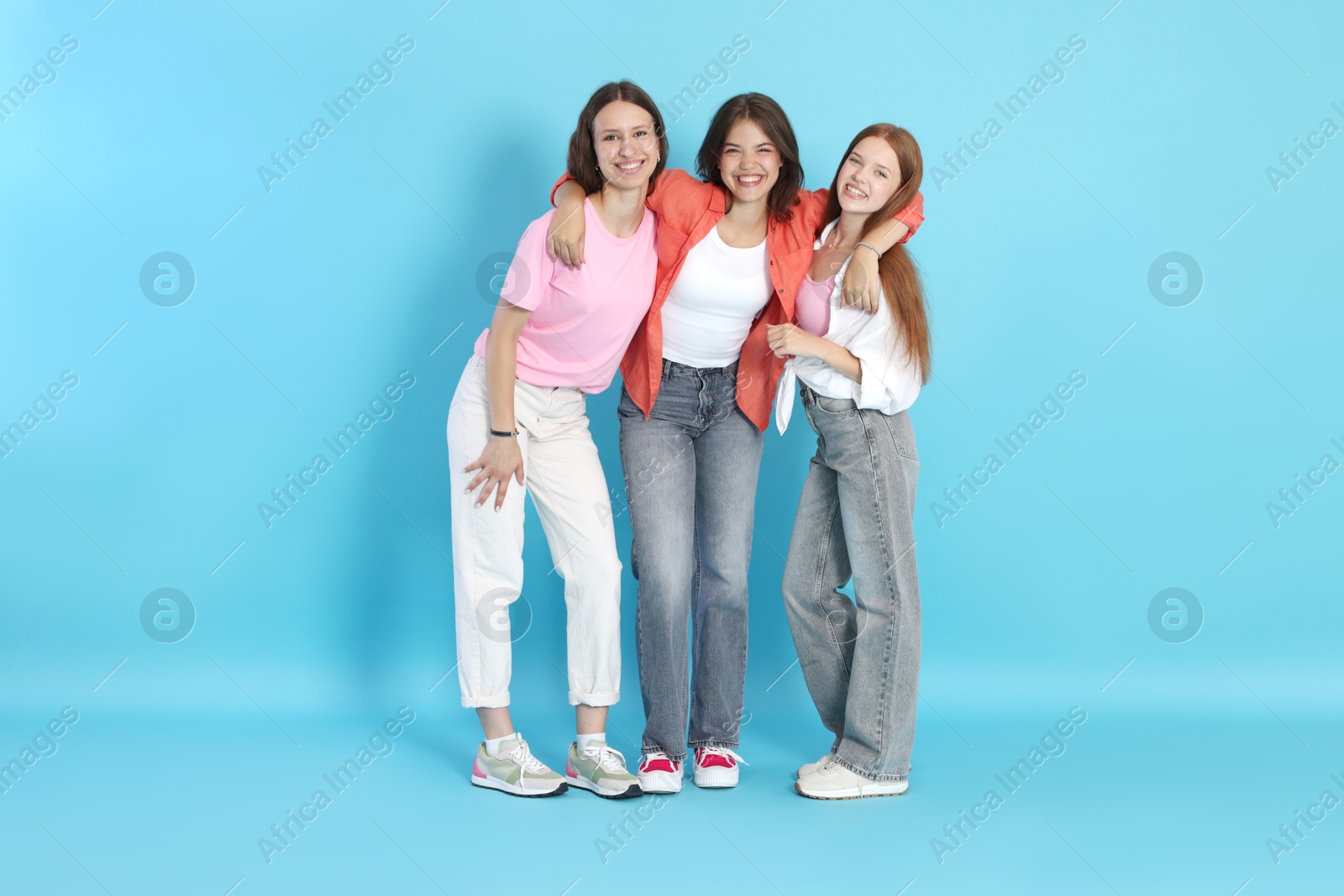 Photo of Full-length portrait of happy teenage friends on light blue background