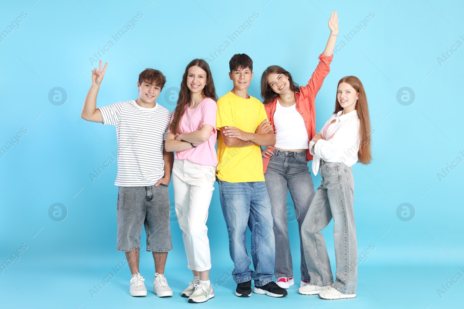 Photo of Full-length portrait of happy teenage friends on light blue background