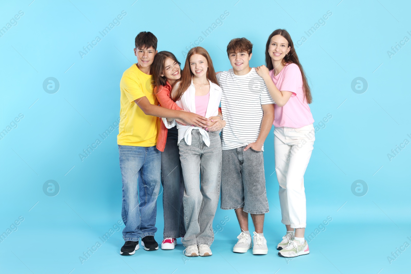 Photo of Full-length portrait of happy teenage friends on light blue background