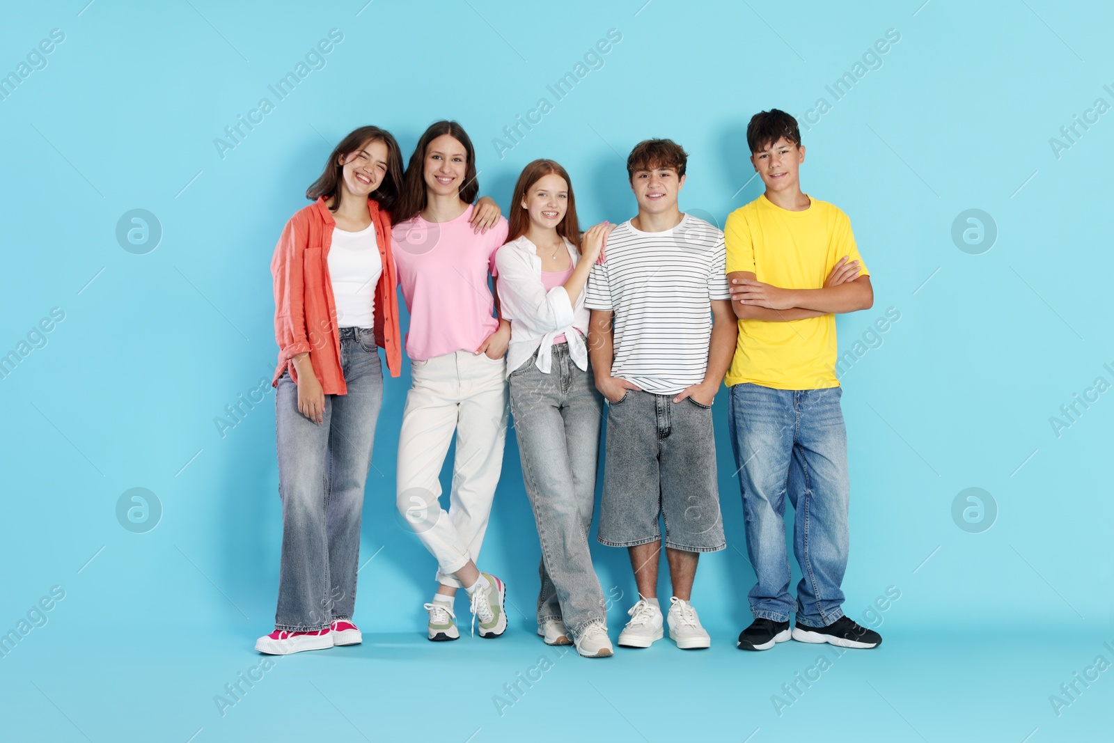 Photo of Full-length portrait of happy teenage friends on light blue background