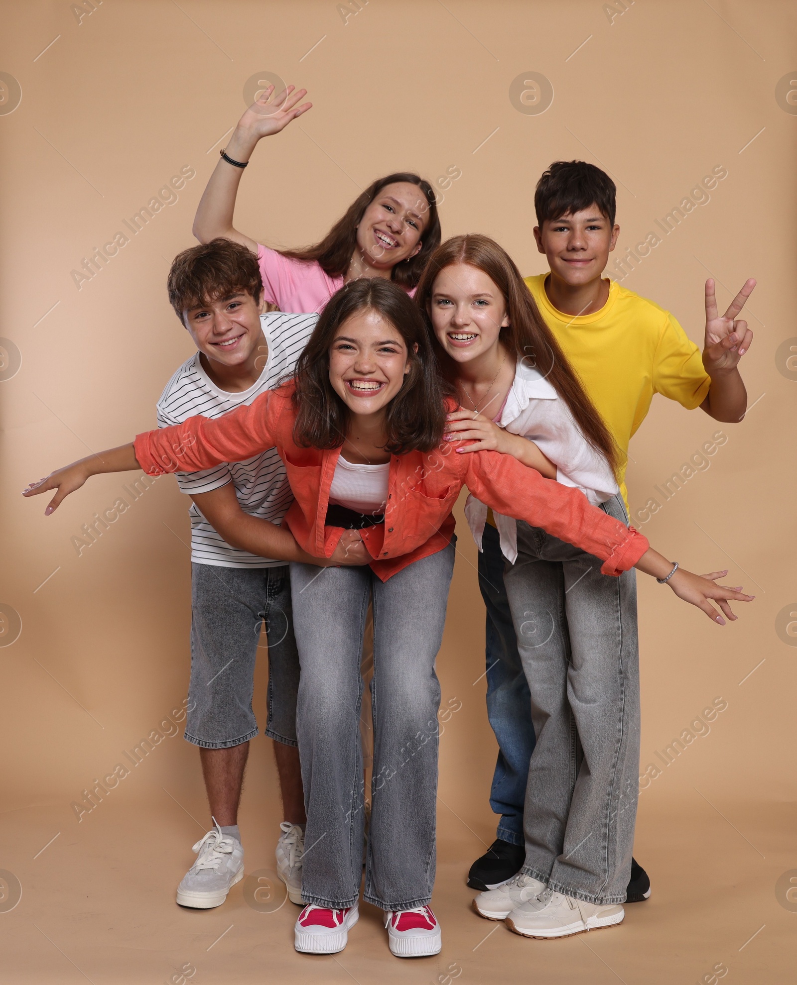 Photo of Portrait of happy teenage friends on beige background
