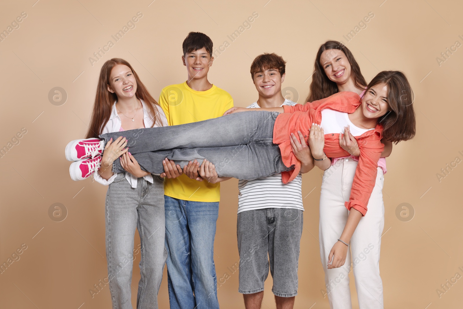 Photo of Portrait of happy teenage friends on beige background