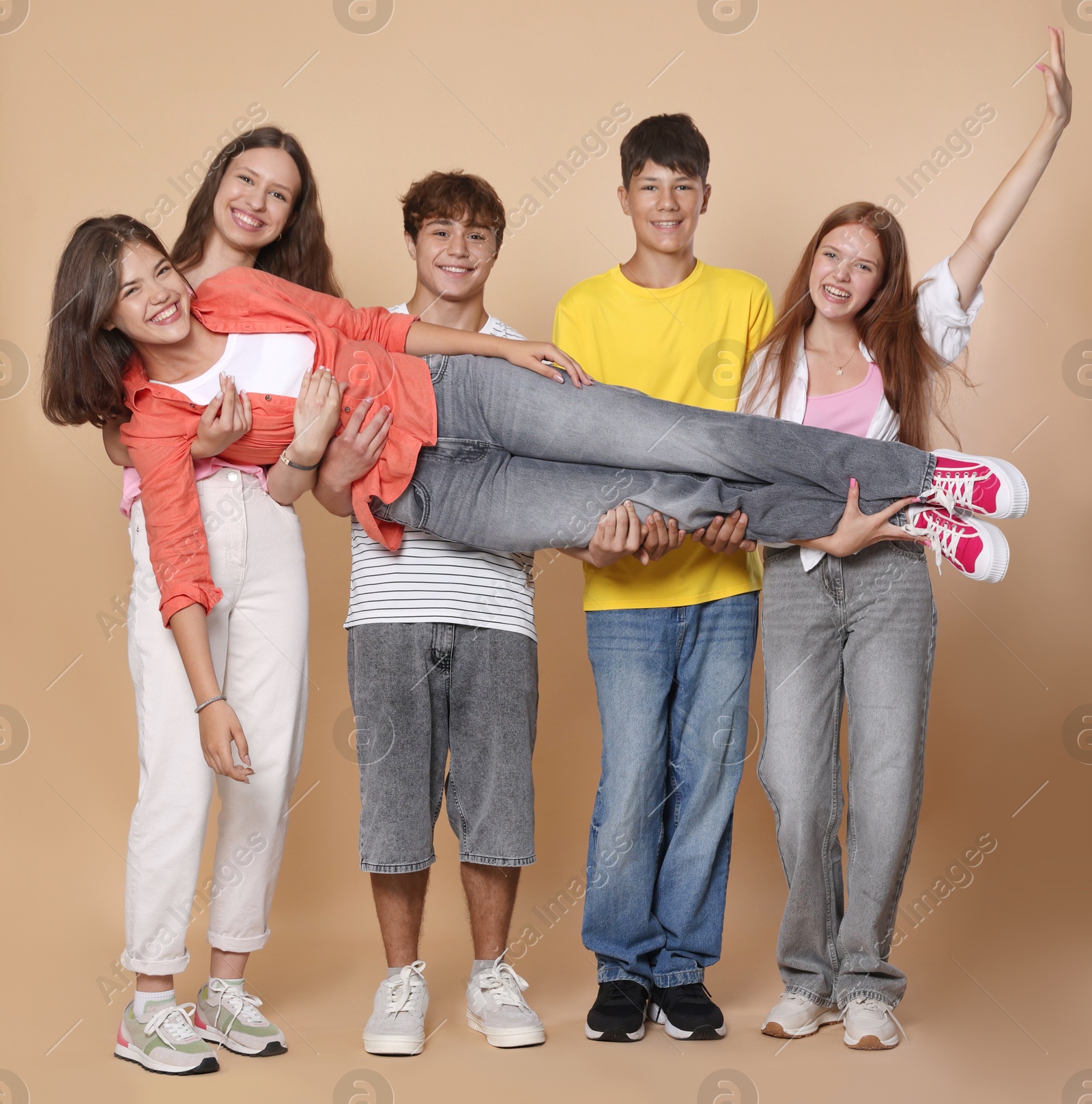 Photo of Full-length portrait of happy teenage friends on beige background