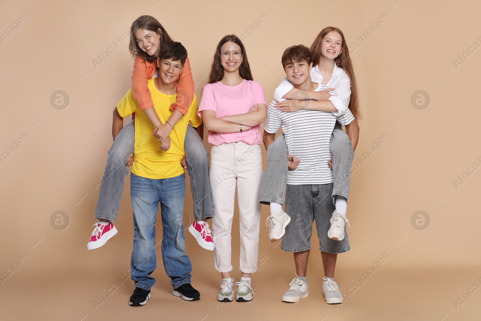 Photo of Full-length portrait of happy teenage friends on beige background