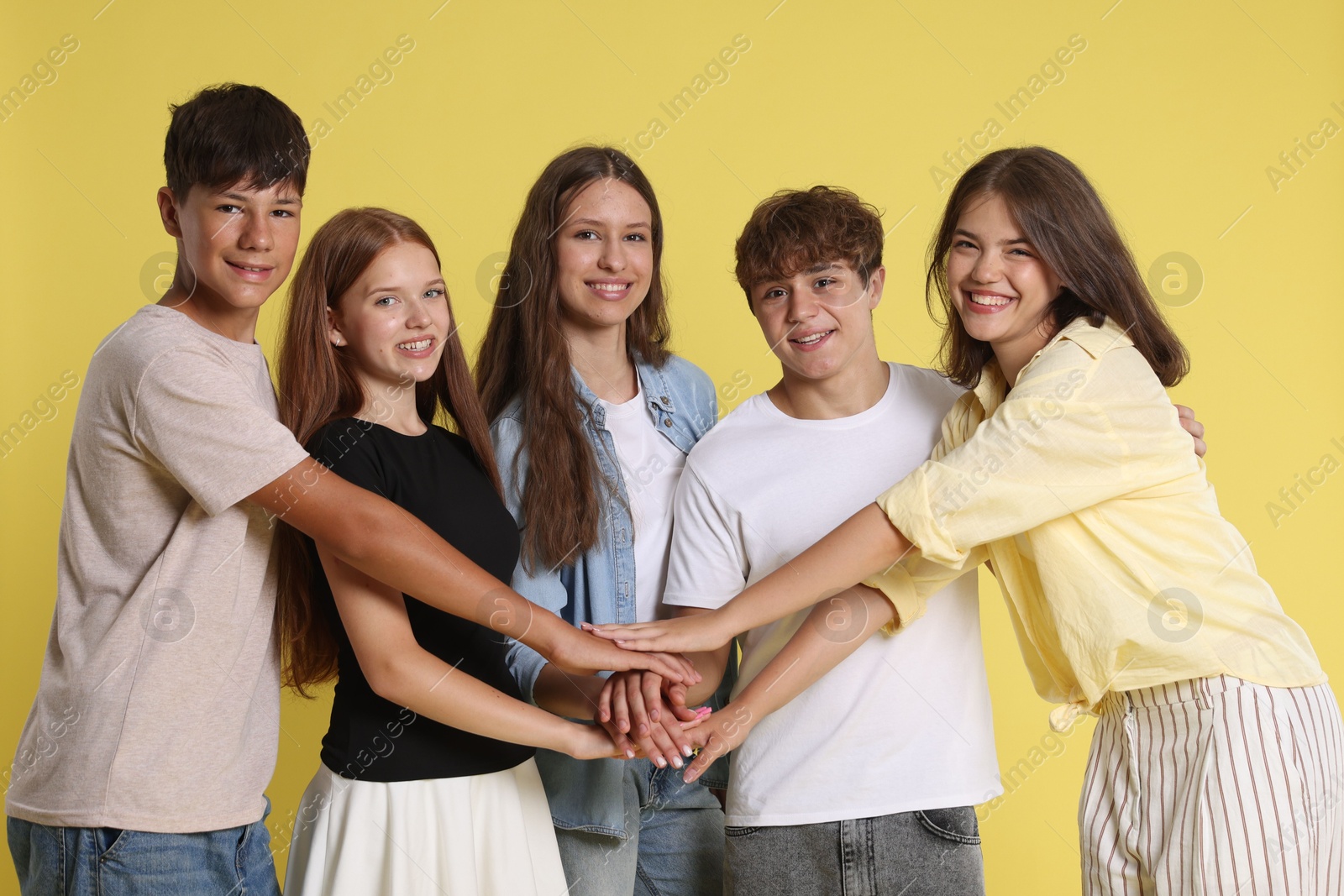 Photo of Portrait of happy teenage friends on yellow background