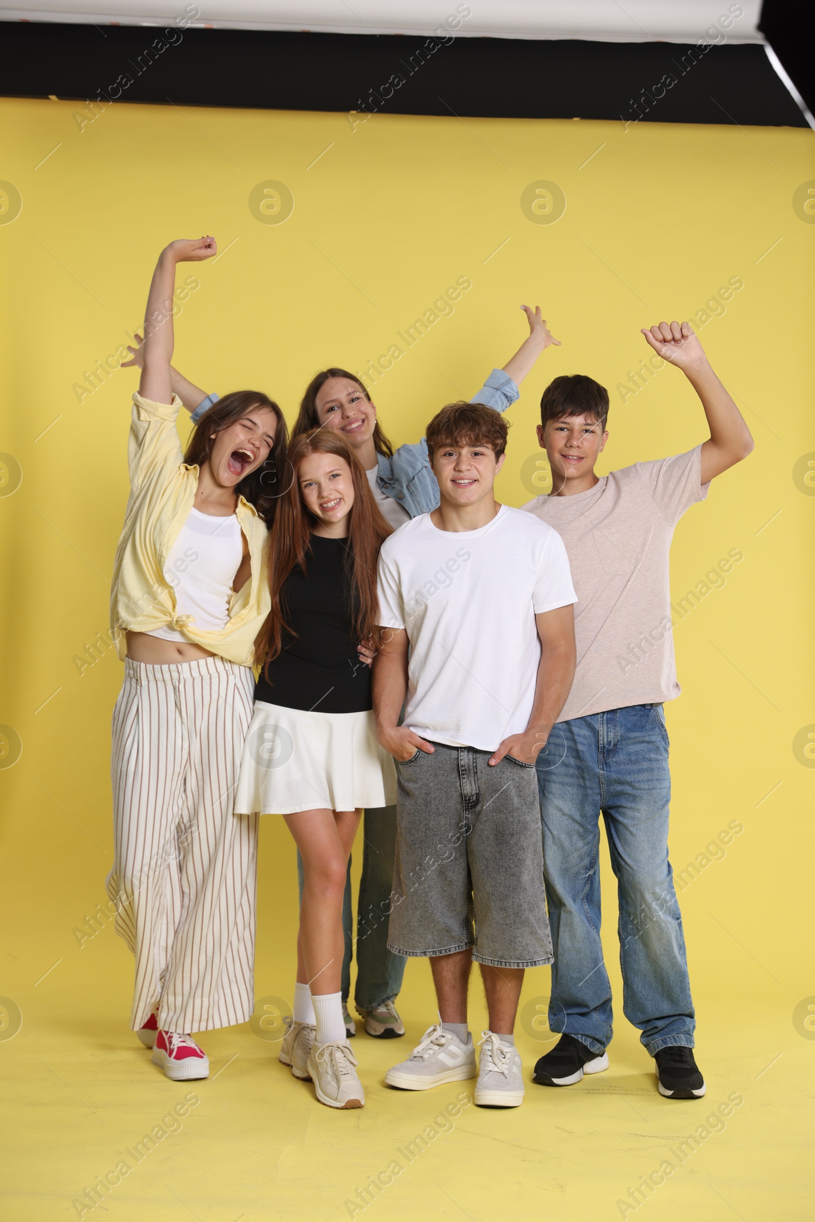 Photo of Full-length portrait of happy teenage friends on yellow background