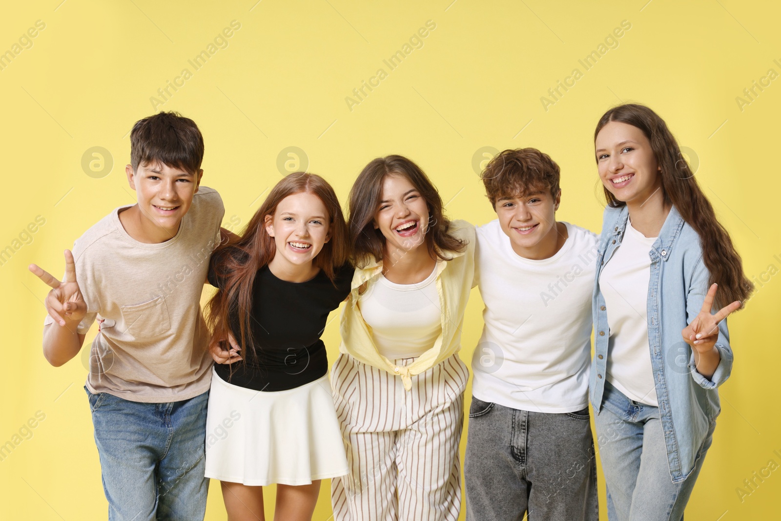 Photo of Portrait of happy teenage friends on yellow background