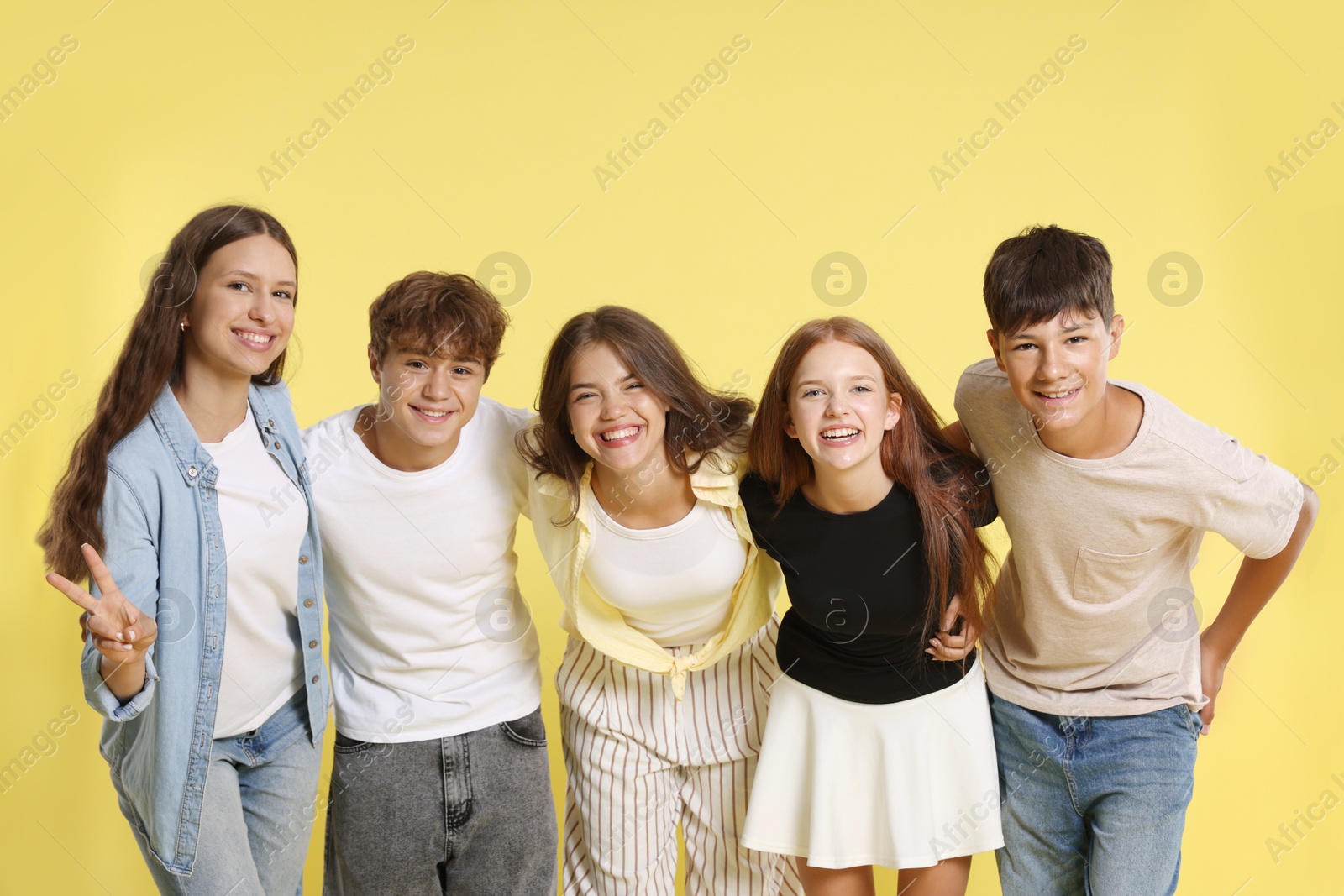 Photo of Portrait of happy teenage friends on yellow background