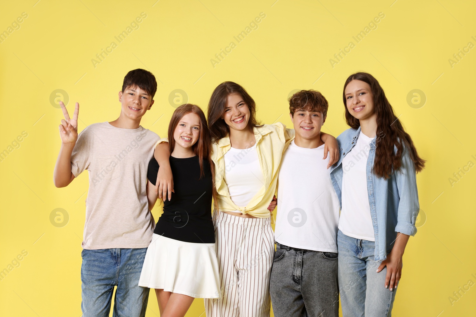 Photo of Portrait of happy teenage friends on yellow background