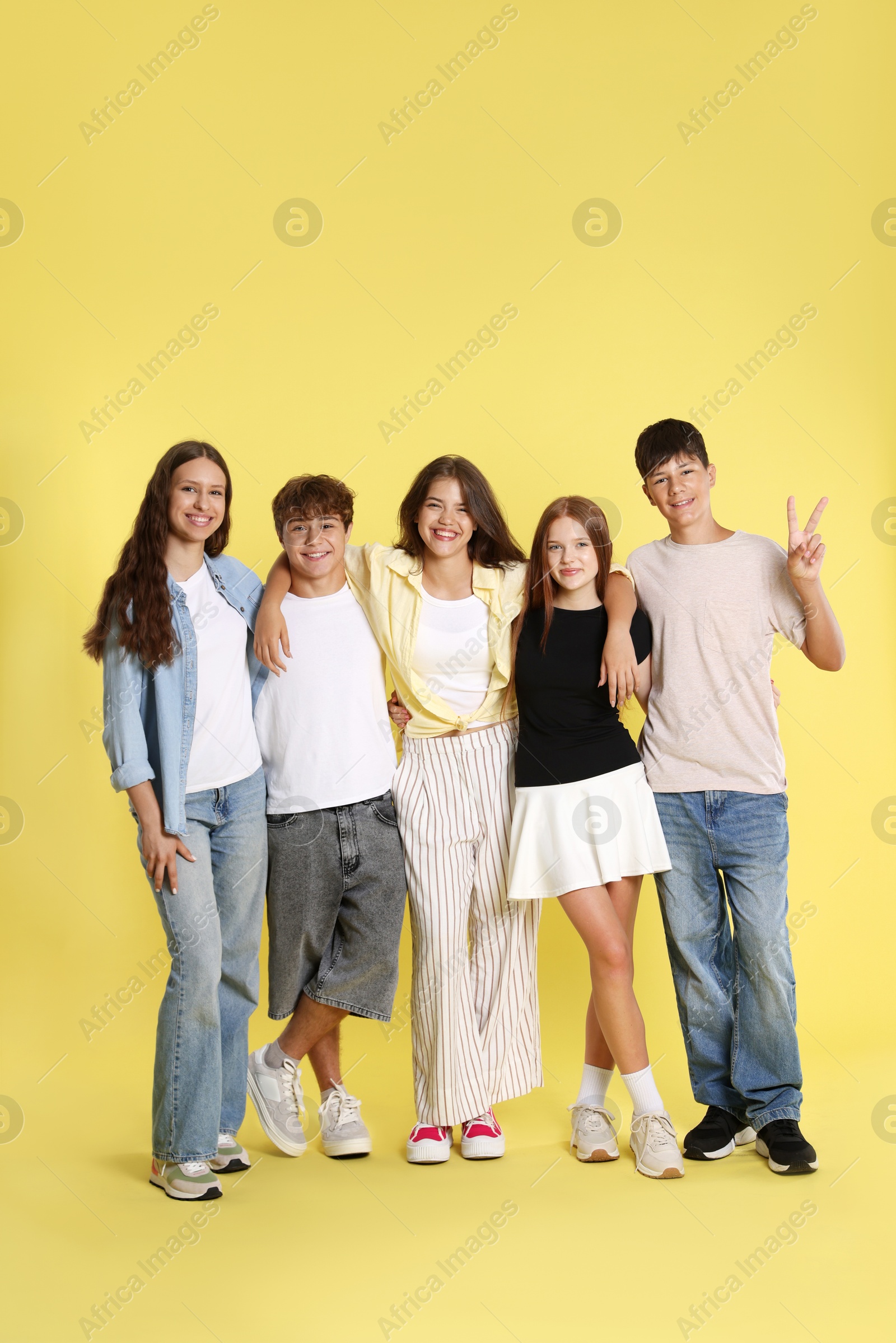Photo of Full-length portrait of happy teenage friends on yellow background