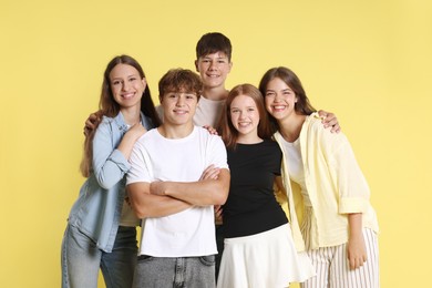 Photo of Portrait of happy teenage friends on yellow background