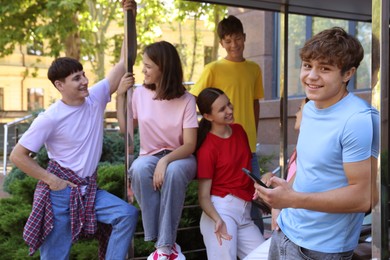 Photo of Group of happy teenage friends spending time together outdoors