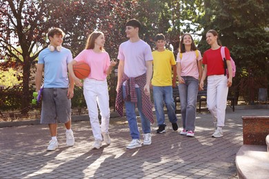 Photo of Group of happy teenage friends spending time together outdoors