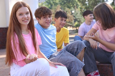 Photo of Group of happy teenage friends spending time together outdoors, selective focus
