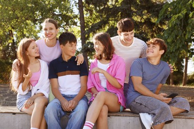 Photo of Group of happy teenage friends spending time together outdoors