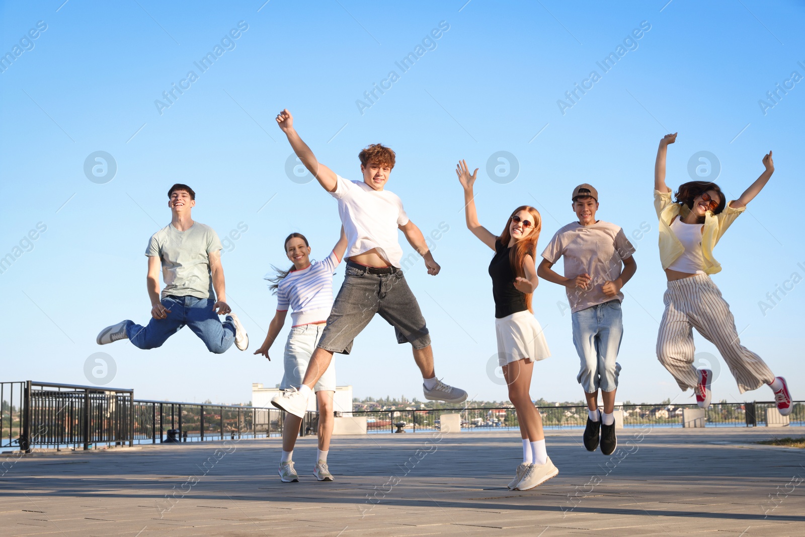 Photo of Group of happy teenage friends jumping outdoors on sunny morning