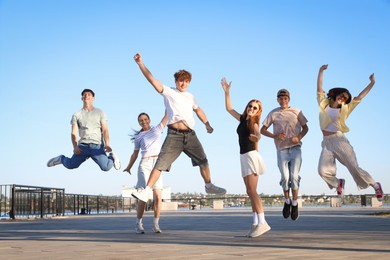 Photo of Group of happy teenage friends jumping outdoors on sunny morning