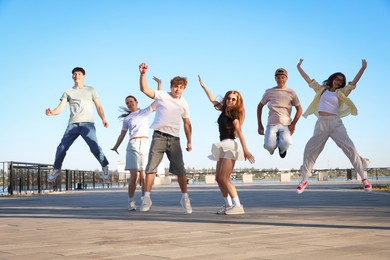 Photo of Group of happy teenage friends jumping outdoors on sunny morning
