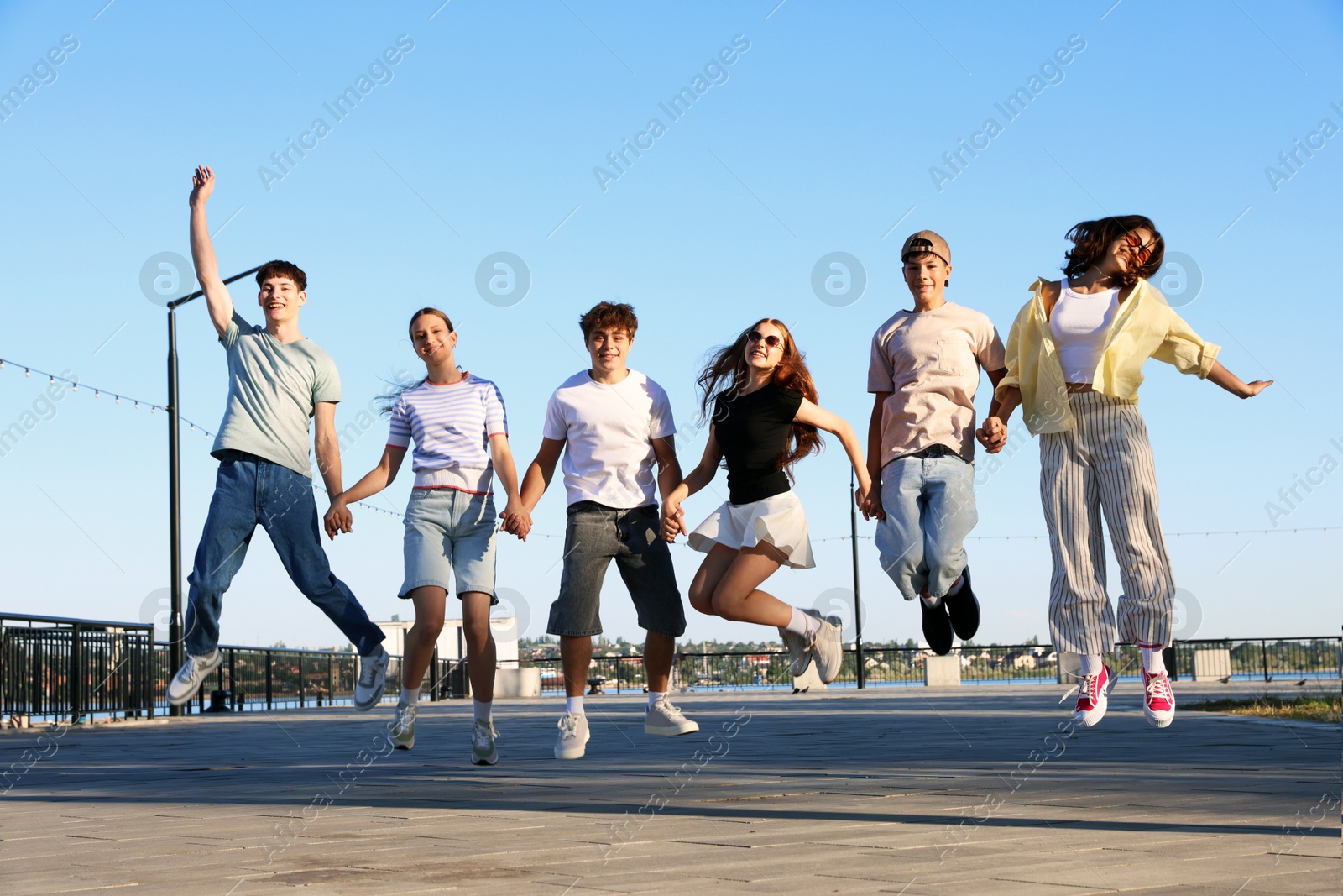 Photo of Group of happy teenage friends jumping outdoors on sunny morning
