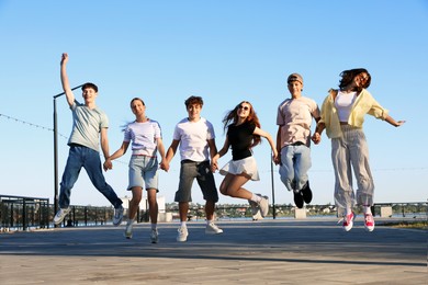 Photo of Group of happy teenage friends jumping outdoors on sunny morning