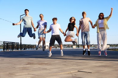 Photo of Group of happy teenage friends jumping outdoors on sunny morning