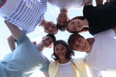 Photo of Group of happy teenage friends spending time together outdoors, bottom view