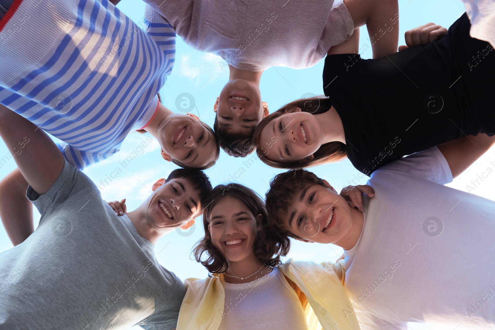 Photo of Group of happy teenage friends spending time together outdoors, bottom view