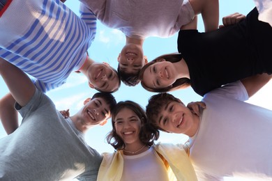 Photo of Group of happy teenage friends spending time together outdoors, bottom view