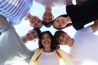 Photo of Group of happy teenage friends spending time together outdoors, bottom view