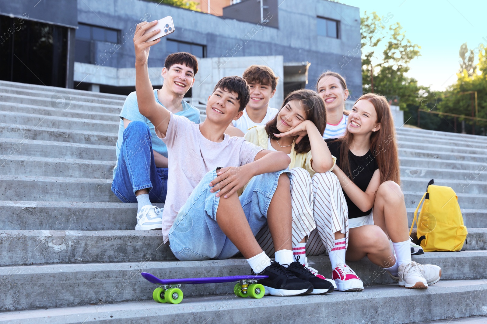 Photo of Group of happy teenage friends taking selfie on steps outdoors