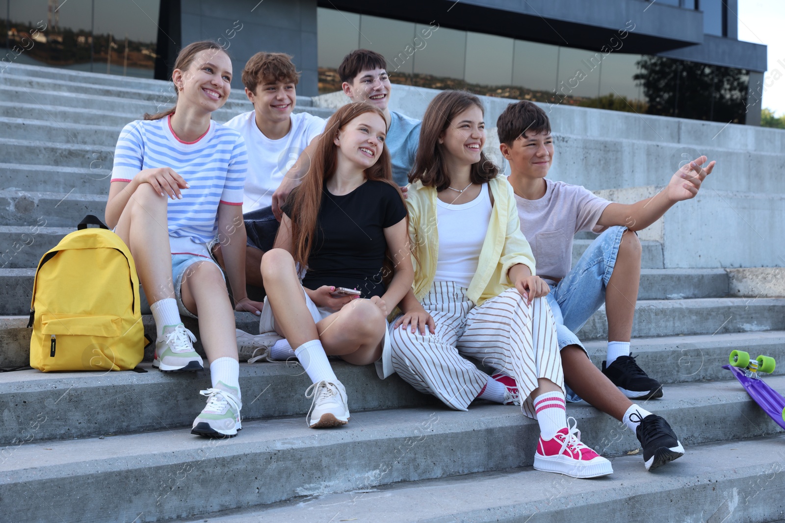 Photo of Group of happy teenage friends spending time together on steps outdoors