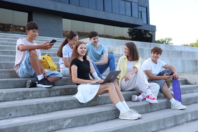 Photo of Group of happy teenage friends spending time together on steps outdoors