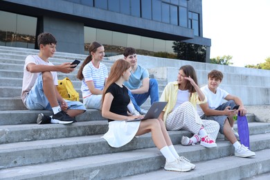 Photo of Group of happy teenage friends spending time together on steps outdoors