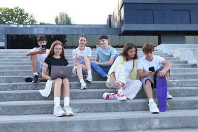Photo of Group of happy teenage friends spending time together on steps outdoors