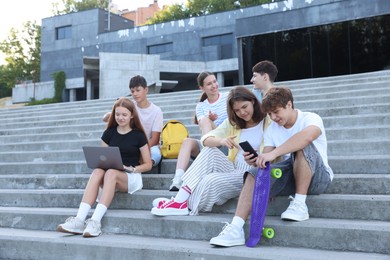 Photo of Group of happy teenage friends spending time together on steps outdoors