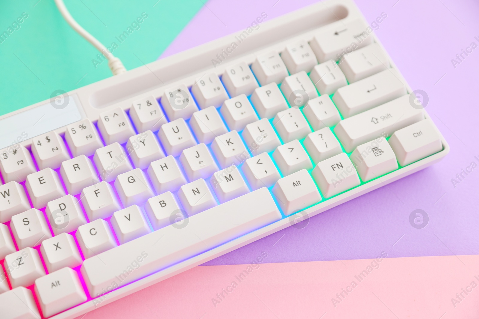 Photo of Modern computer keyboard with RGB lighting on color background, above view