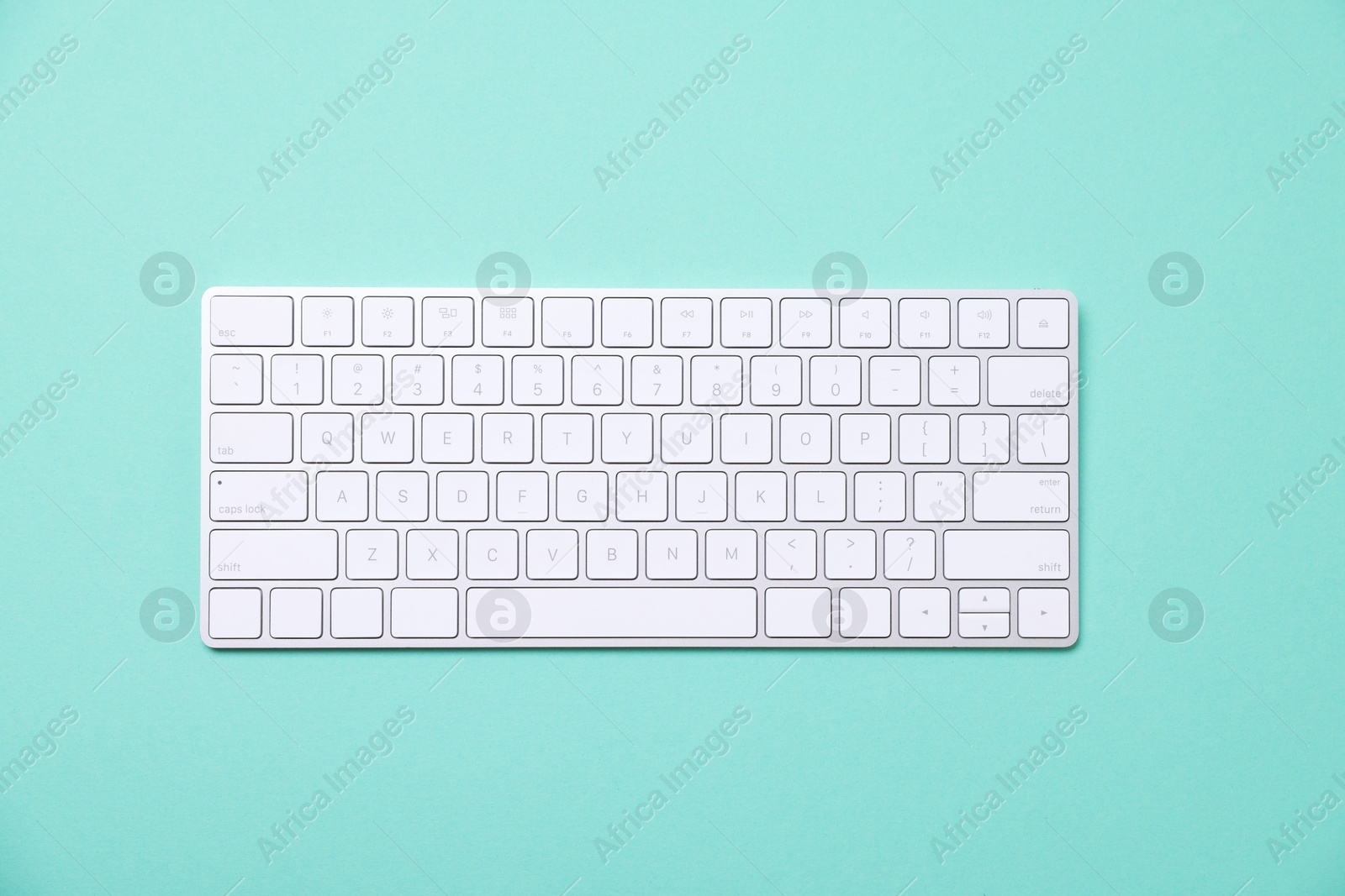 Photo of Modern wireless computer keyboard on turquoise background, top view