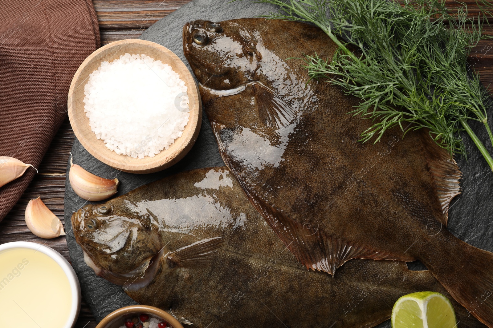 Fresh flounder fish, spices and products on wooden table, flat lay. Raw seafood Photo of Fresh flounder fish, spices and products on wooden table, flat lay. Raw seafood