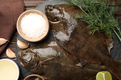 Photo of Fresh flounder fish, spices and products on wooden table, flat lay. Raw seafood