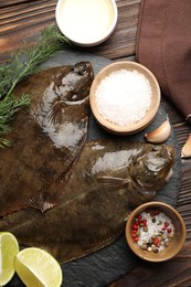 Photo of Fresh flounder fish, spices and products on wooden table, flat lay. Raw seafood